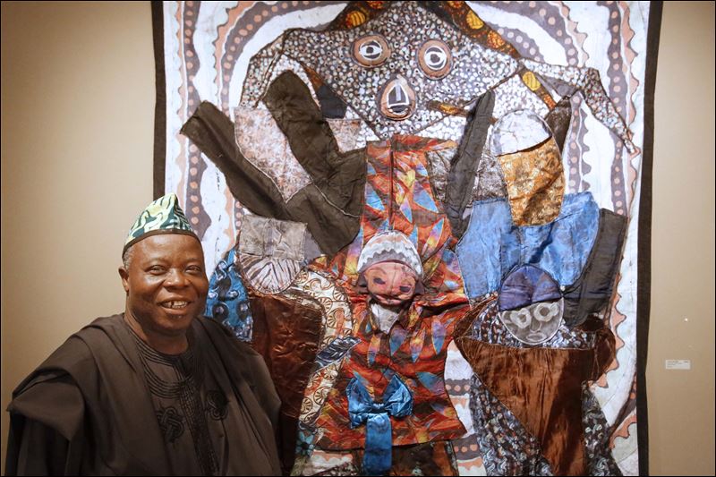 Tunde stands with one of his batik quilts at the Hudson Gallery in Sylvania, Ohio. Photo: Toledo Blade/Katie Rausch